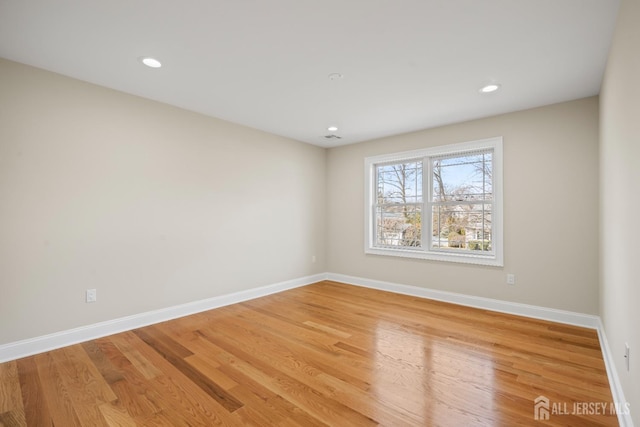 empty room with light wood finished floors, baseboards, recessed lighting, and visible vents