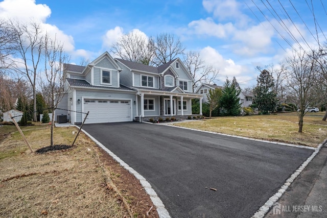 view of front of home with aphalt driveway, an attached garage, covered porch, and a front yard