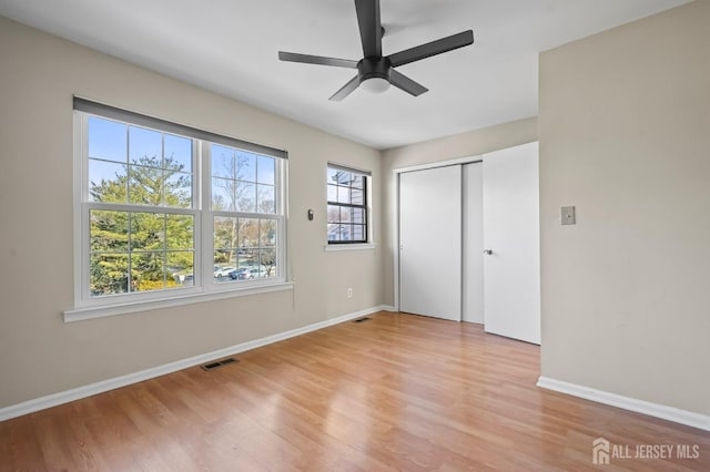 unfurnished bedroom featuring light wood-style floors, visible vents, a closet, and baseboards