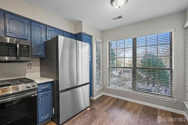 kitchen with visible vents, blue cabinetry, stainless steel appliances, and dark wood-style flooring