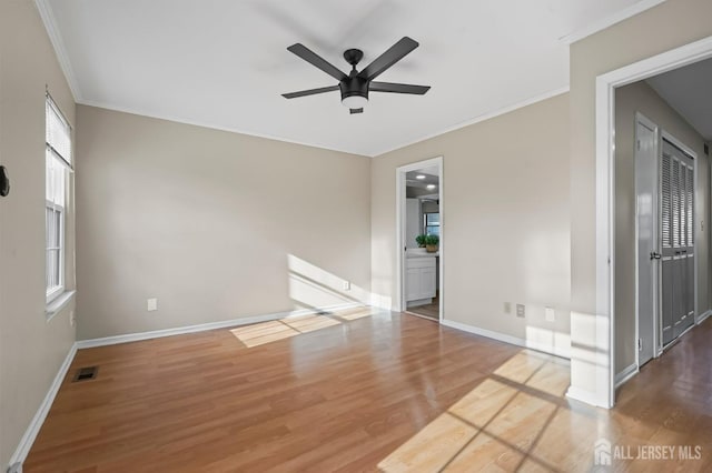 spare room featuring ceiling fan, wood finished floors, crown molding, and baseboards