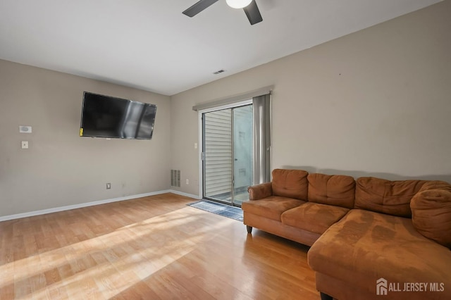 living room featuring baseboards, visible vents, light wood finished floors, and ceiling fan