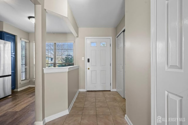 doorway with baseboards and tile patterned flooring