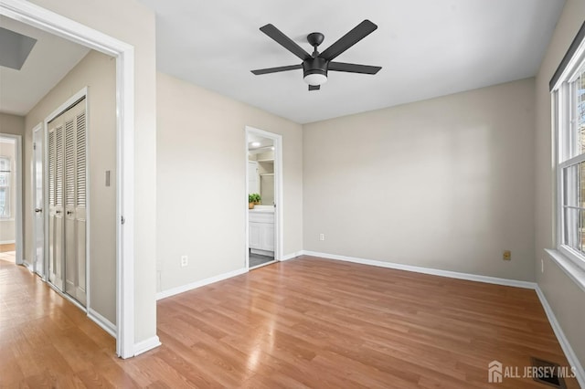 unfurnished bedroom featuring a closet, baseboards, ensuite bath, and light wood-style floors