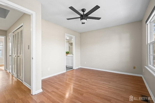 unfurnished bedroom with light wood-style flooring, baseboards, a closet, ensuite bath, and a ceiling fan