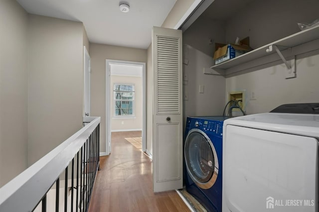 laundry area featuring laundry area, light wood-style floors, baseboards, and washer and clothes dryer