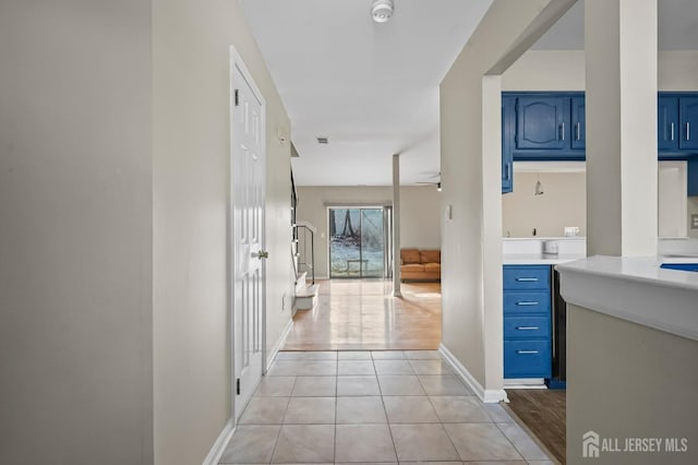 hall with light tile patterned flooring, visible vents, and baseboards