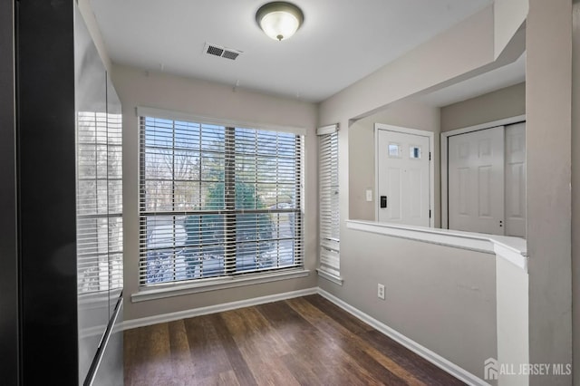 empty room featuring wood finished floors, baseboards, and visible vents