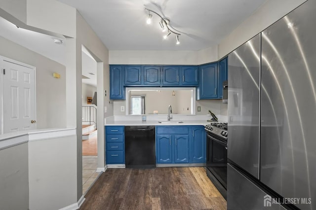 kitchen with black appliances, blue cabinetry, and a sink