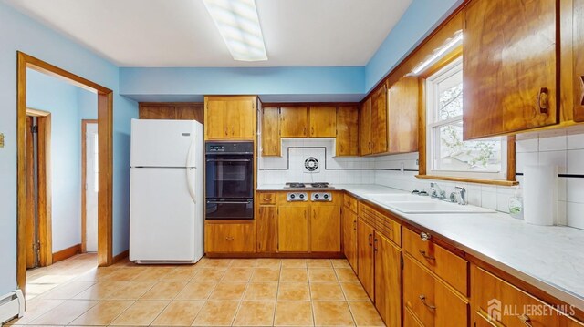 190 S Moetz Dr S, Milltown, NJ 08850 - kitchen with black oven, freestanding refrigerator, a sink, baseboard heating, and brown cabinetry