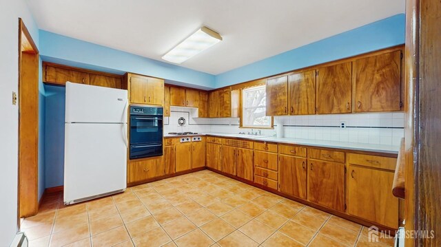 190 S Moetz Dr S, Milltown, NJ 08850 - kitchen with freestanding refrigerator, black oven, brown cabinets, and a warming drawer
