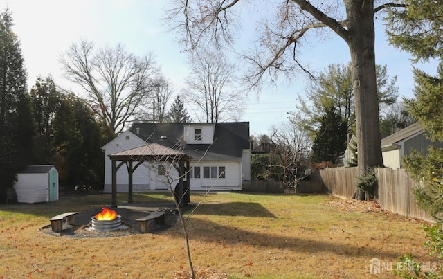 back of house with an outbuilding, a gazebo, an outdoor fire pit, fence, and a shed