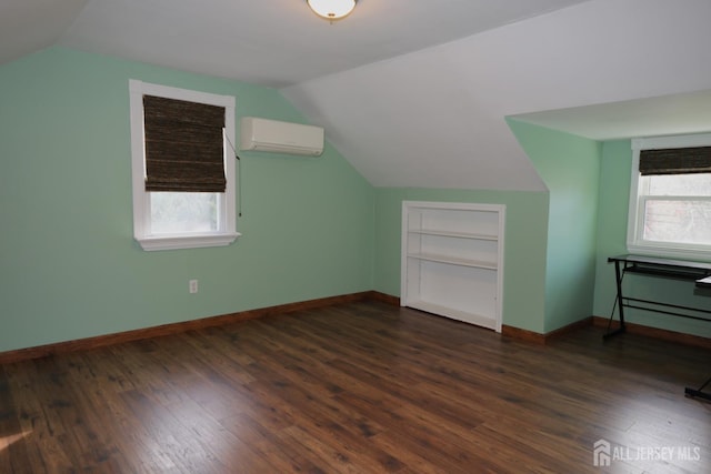 bonus room with a wealth of natural light, an AC wall unit, dark wood finished floors, and baseboards