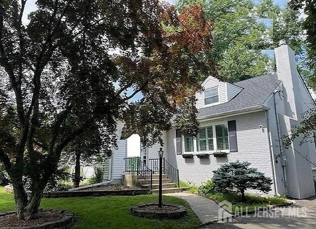 view of front of home featuring brick siding and a chimney