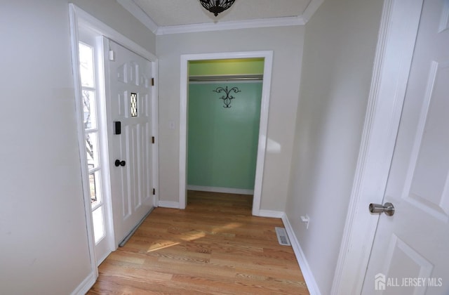 foyer entrance featuring ornamental molding, light wood finished floors, visible vents, and baseboards