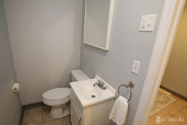 half bath featuring vanity, toilet, and tile patterned floors