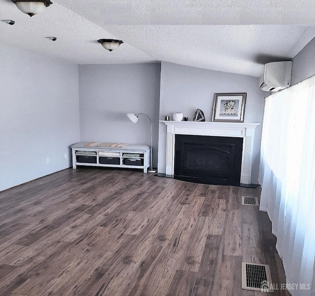 unfurnished living room featuring wood finished floors, visible vents, a fireplace, and a wall mounted AC