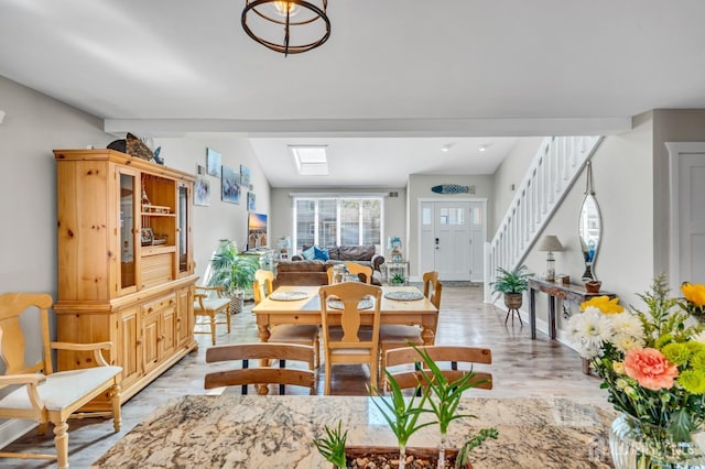 dining space featuring stairway, light wood finished floors, and vaulted ceiling