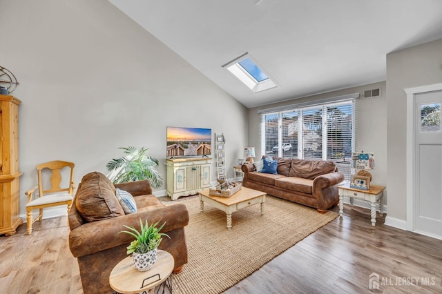 living area featuring visible vents, baseboards, wood finished floors, high vaulted ceiling, and a skylight