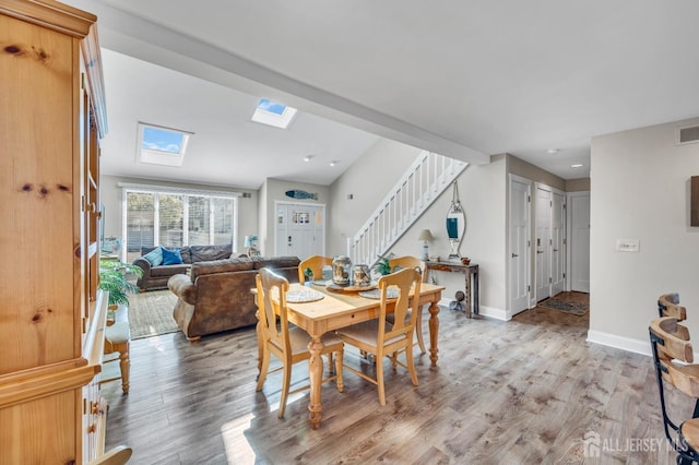 dining room featuring stairway, visible vents, light wood-style flooring, and a skylight