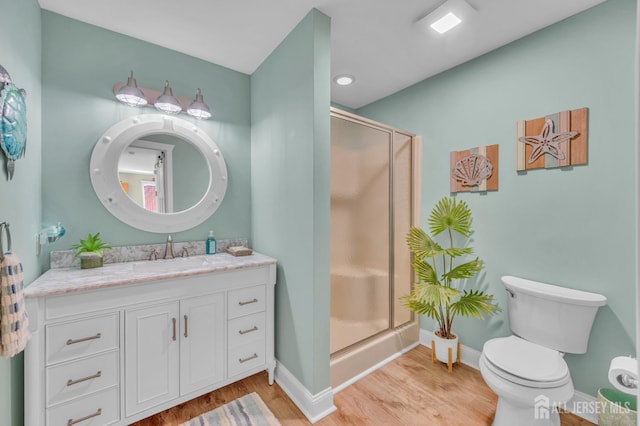 full bath with vanity, toilet, a stall shower, baseboards, and wood finished floors