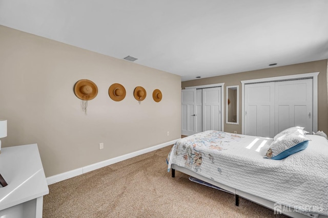 carpeted bedroom featuring baseboards, visible vents, and multiple closets