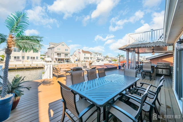 wooden deck with outdoor dining space, area for grilling, a boat dock, and a residential view