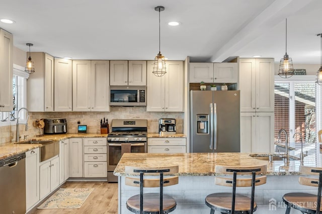 kitchen featuring appliances with stainless steel finishes, a healthy amount of sunlight, a kitchen breakfast bar, and a sink