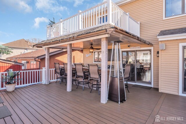 wooden deck with ceiling fan and a bar