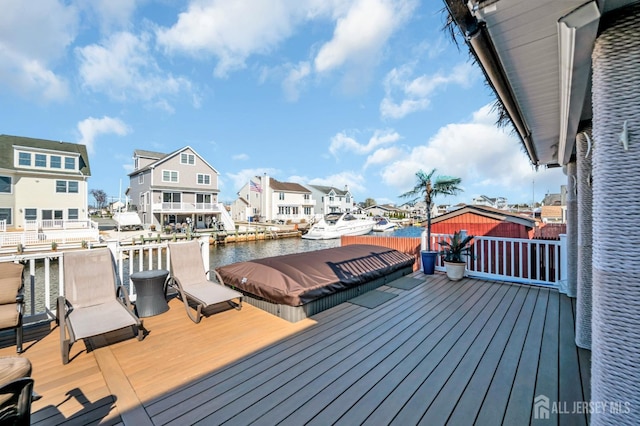 wooden terrace featuring a residential view, a water view, and a floating dock