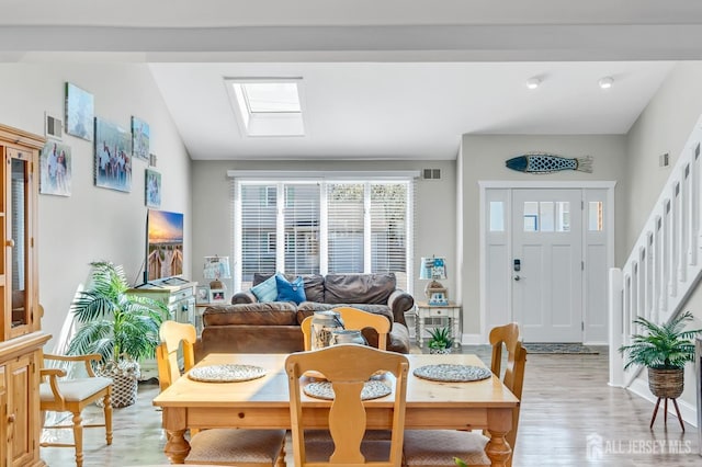 dining area featuring stairs, visible vents, vaulted ceiling, and light wood-type flooring