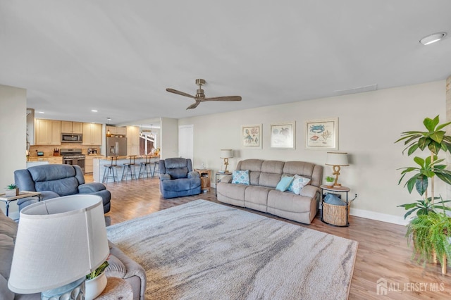 living area with baseboards, recessed lighting, ceiling fan, and light wood-style floors