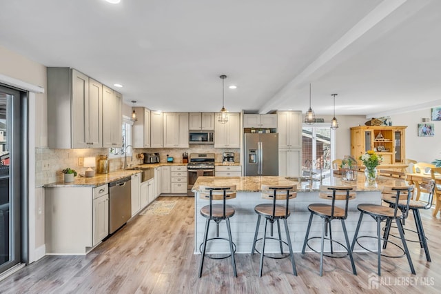 kitchen with a breakfast bar, stainless steel appliances, decorative backsplash, and a sink