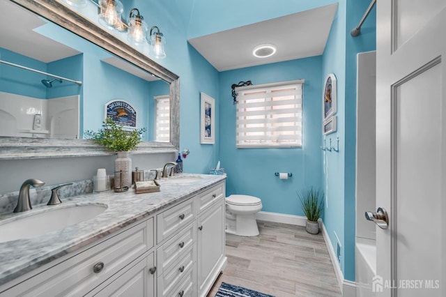 full bath with toilet, double vanity, a sink, and wood finished floors
