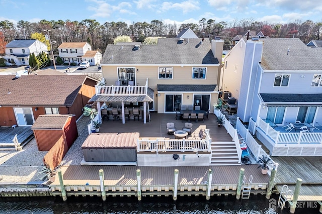 back of property with a residential view, an outdoor hangout area, outdoor dining area, and a deck with water view