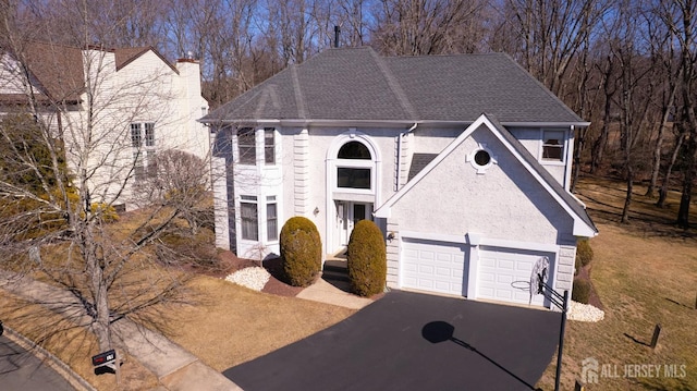 view of front of house with driveway, a chimney, roof with shingles, and stucco siding