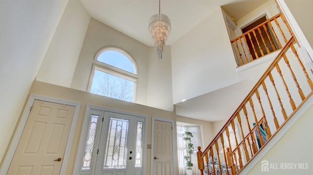 entryway with a chandelier, a towering ceiling, and stairway