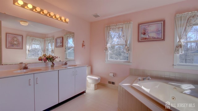 bathroom with a whirlpool tub, double vanity, toilet, tile patterned floors, and baseboards