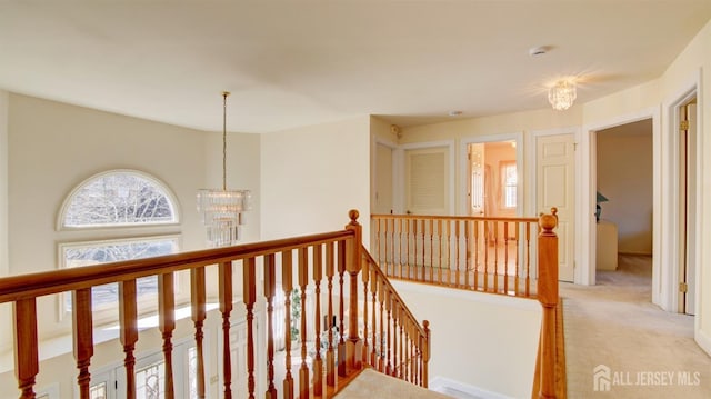 corridor featuring an upstairs landing, a chandelier, and light carpet
