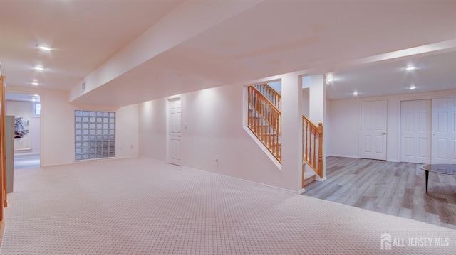finished below grade area featuring stairs, baseboards, carpet, and wood finished floors