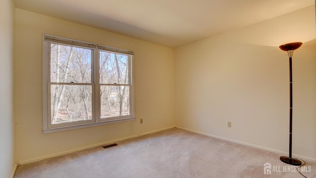 unfurnished room featuring light colored carpet and baseboards