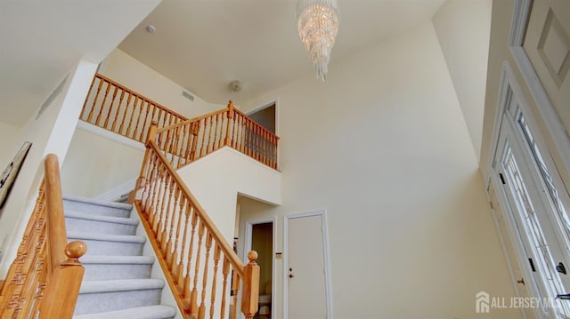 staircase with a towering ceiling and a chandelier
