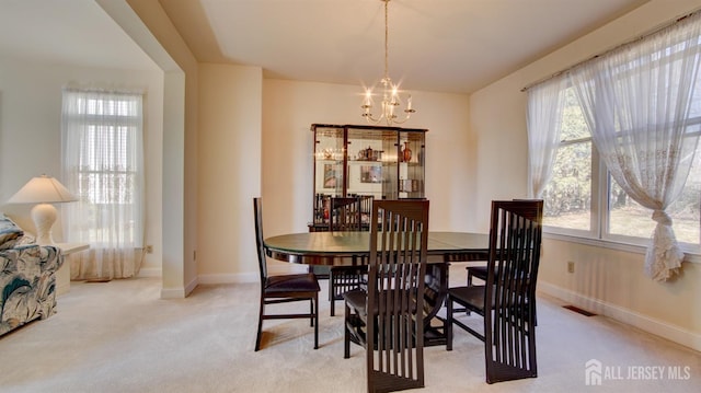 dining room with a chandelier, light carpet, and baseboards