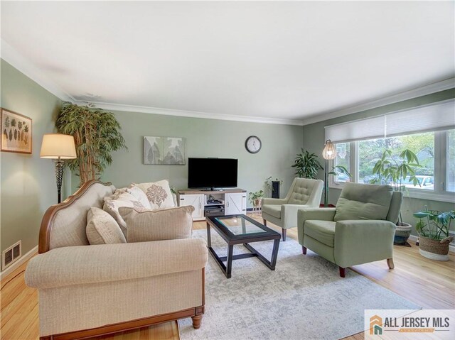 living area featuring light wood finished floors, crown molding, and baseboards