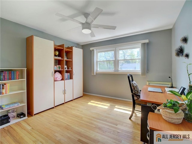 home office featuring wood finished floors, a ceiling fan, and baseboards