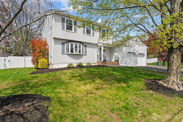 colonial-style house featuring fence, an attached garage, a front yard, and aphalt driveway