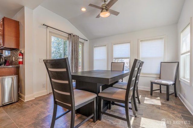 dining space with lofted ceiling, ceiling fan, baseboards, and dark stone finish flooring