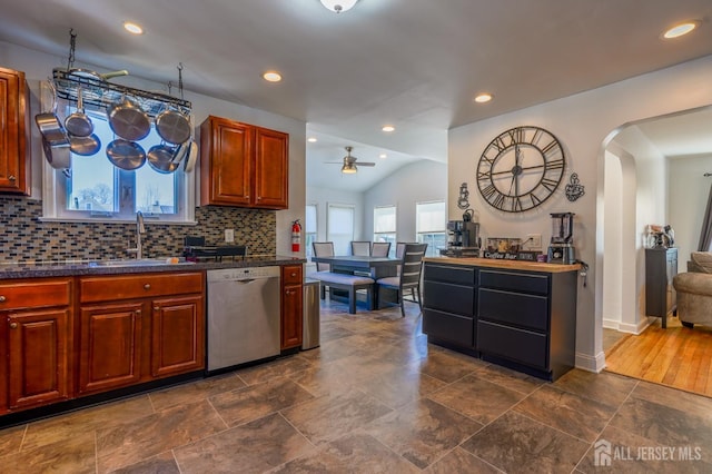 kitchen with dishwasher, a sink, ceiling fan, dark countertops, and lofted ceiling