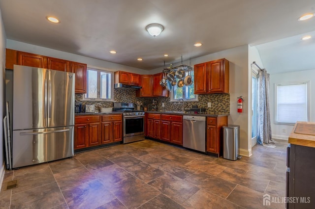 kitchen with stainless steel appliances, under cabinet range hood, baseboards, dark countertops, and recessed lighting