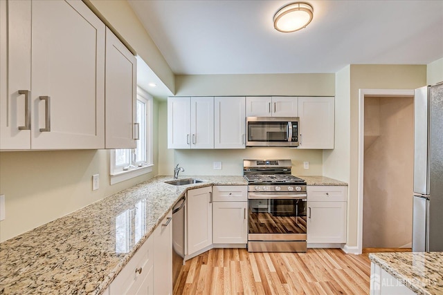 kitchen featuring sink, stainless steel appliances, white cabinetry, and light stone countertops